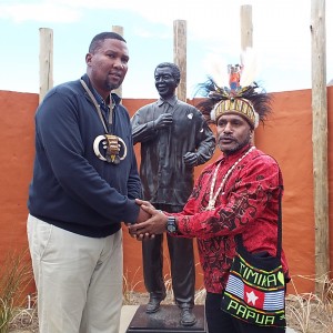 Benny Wenda shaking hands with Chief Zwelivelile Mandela at Mveso, in front of the statue of Nelson Mandela.